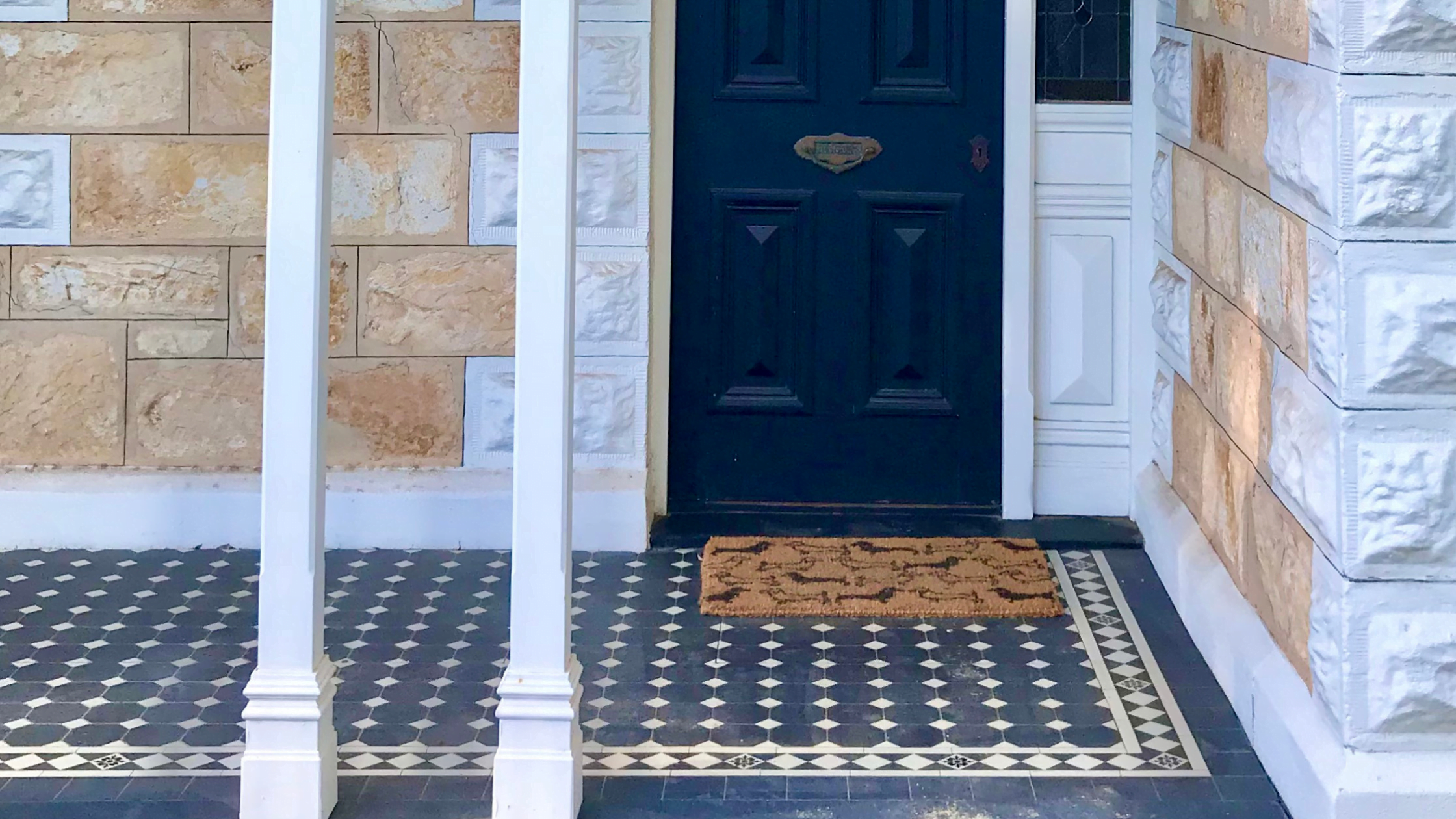 Tiled front porch and black painted front door of a heritage home.