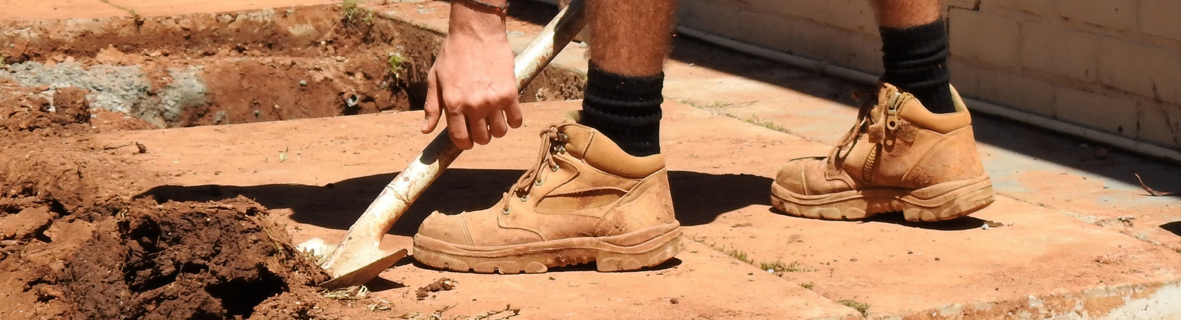 Close up photo of the work boots of a construction worker digging dirt