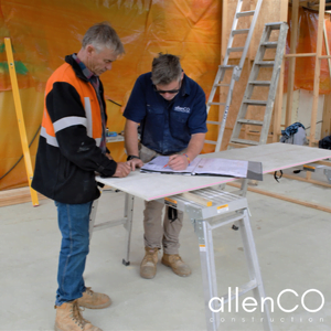 Two builders are checking construction plans on a table