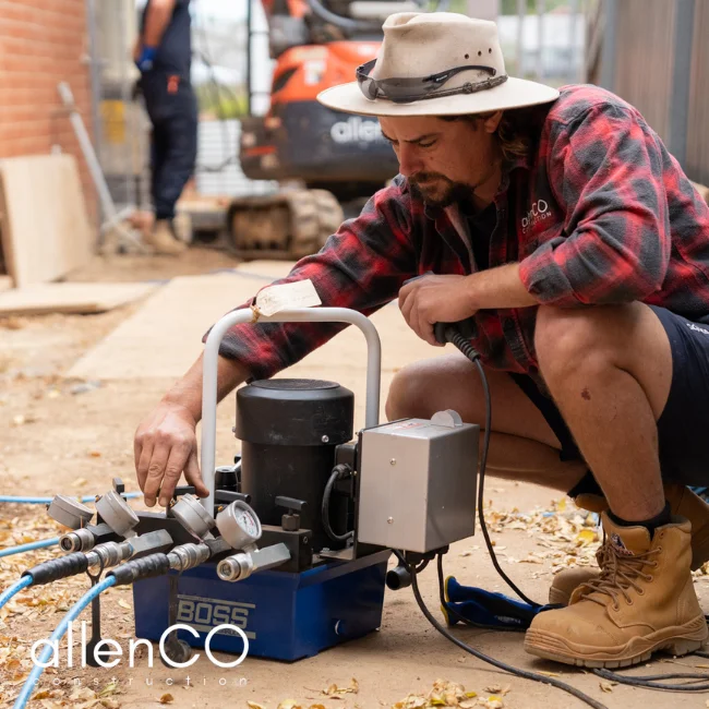 Young man using hydrolic equipment for underpinning