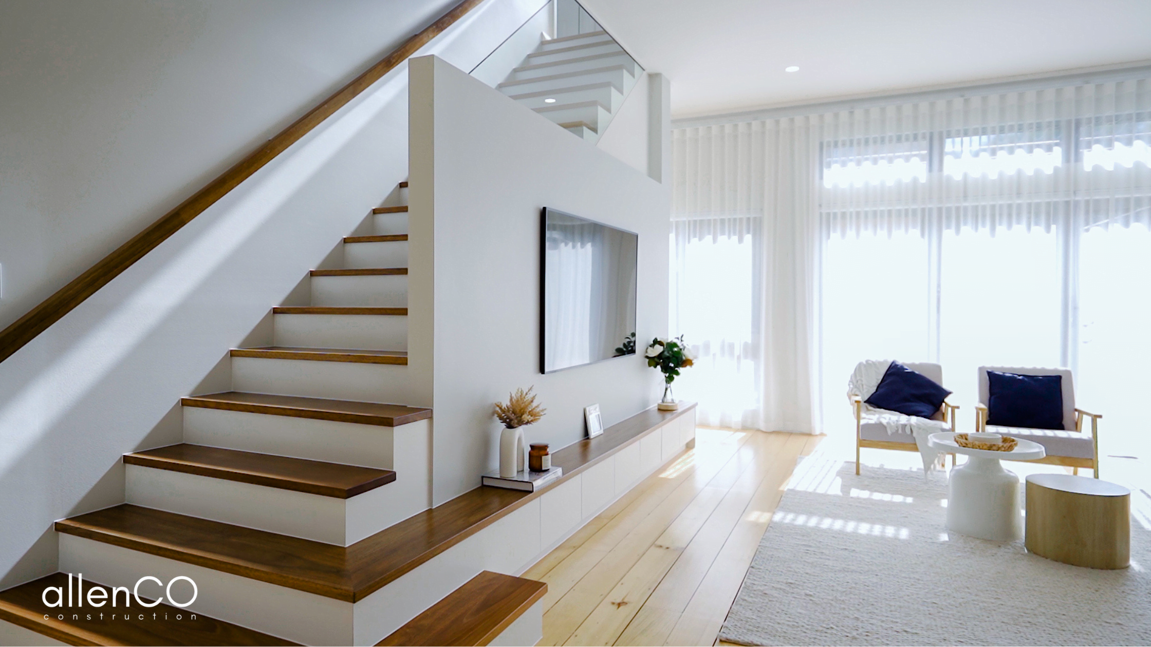 Newly built modern living room with wall mounted TV and a feature staircase.